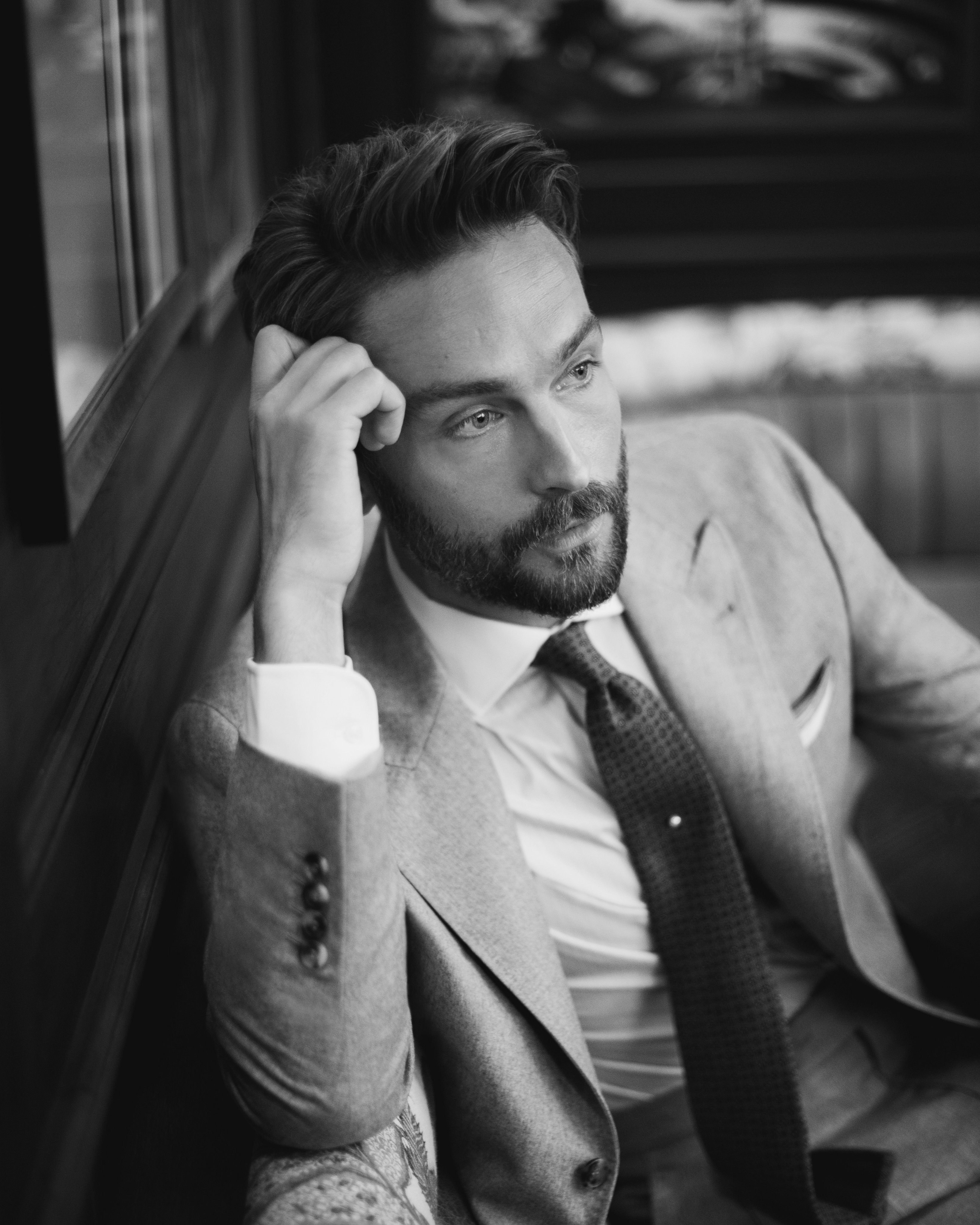 Black and white photo of Tom Mison in a suit