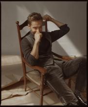 Tom is sprawled in a chair, dressed in velvet vest and trousers. Photo by Matthew Priestley.